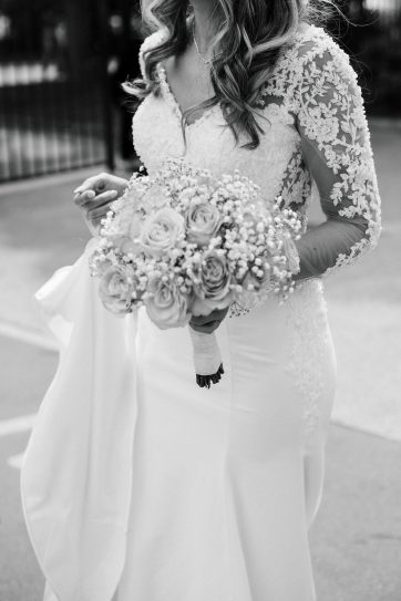Mariée en robe en dentelle de chantilly tenant un bouquet de roses, capturée dans un style fine art par un photographe de mariage à Paris