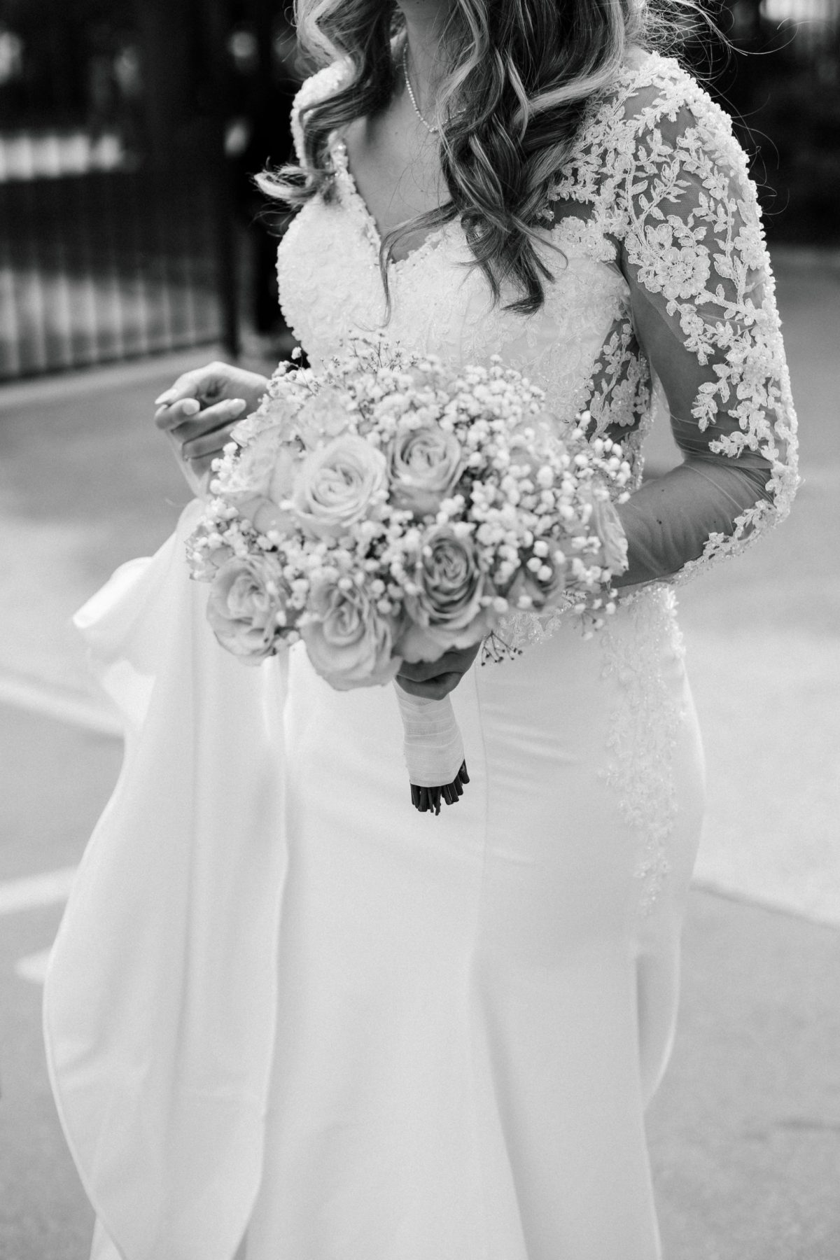 Mariée en robe en dentelle de chantilly tenant un bouquet de roses, capturée dans un style fine art par un photographe de mariage à Paris