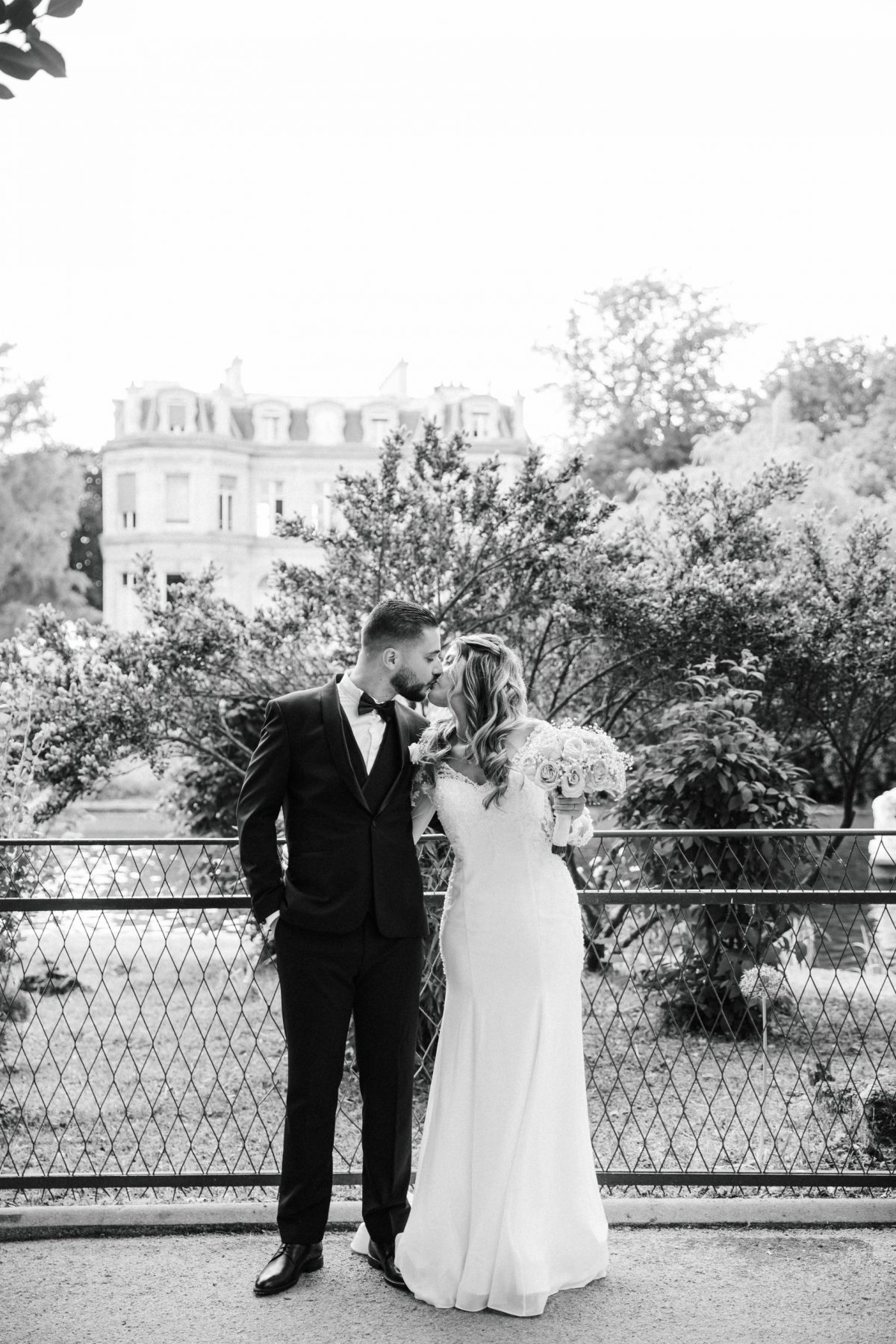 Un couple de mariés échange un baiser passionné, photographié en noir et blanc Tarifs photographe mariage fine art à Paris