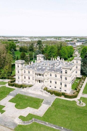 default | Séverine Alves - Paris wedding photographer, France A large stone castle-like mansion with symmetrical towers and manicured gardens, viewed from above.